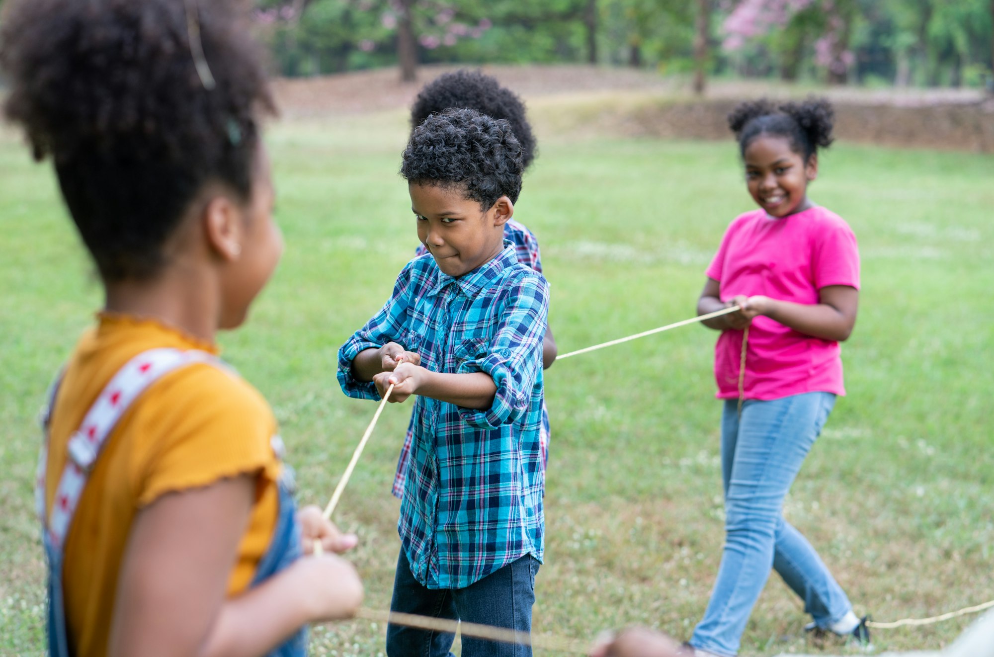 Happy African American childrens playing rope tug of war in the park, Education outdoor concept